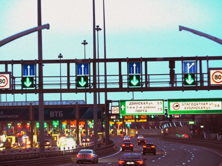 many cars travelling under a busy highway with green lights