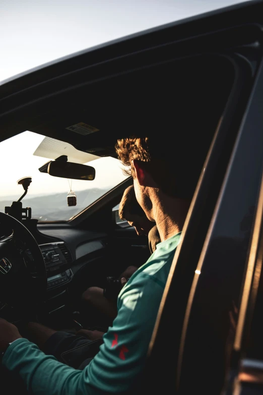 man driving a car with sun in the back