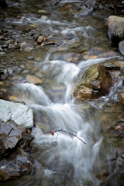 small stream of water next to a stone cliff