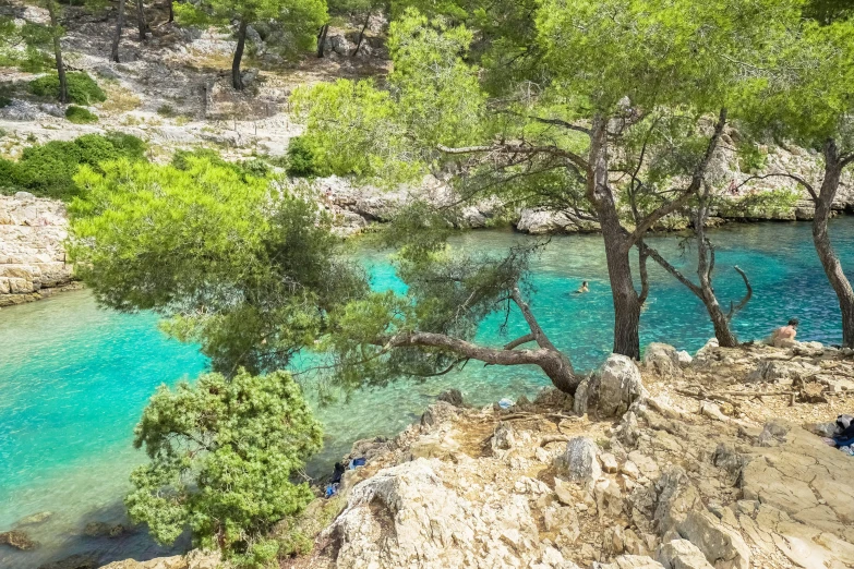 many people stand on a rock near the water