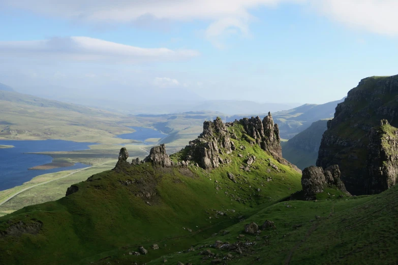 a large cliff sitting on top of a lush green hillside