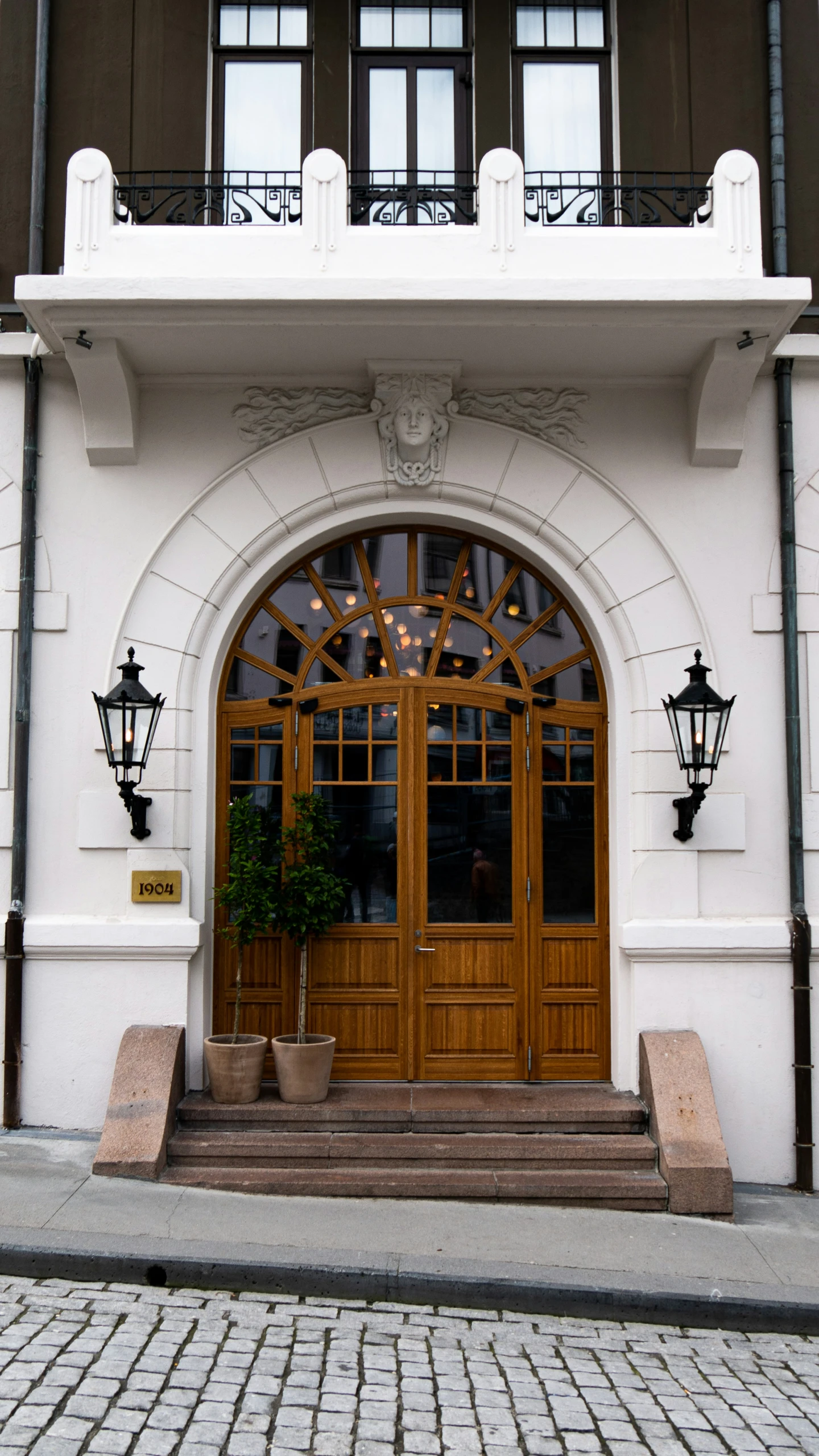 the front of a two story building with a plant on its balcony