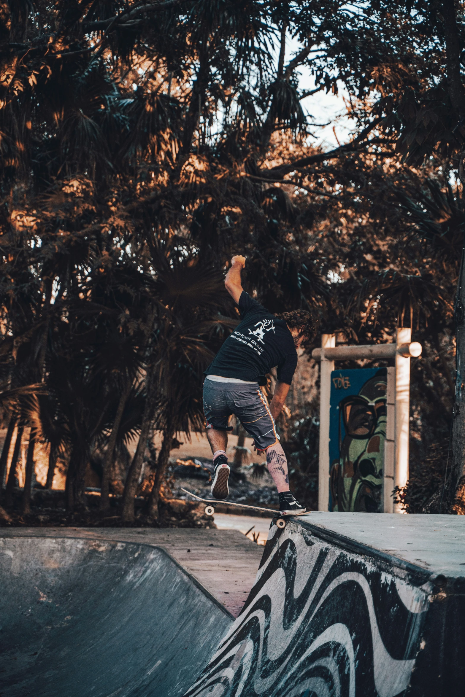 skateboarder in black shirt and gray shorts jumping off ramp