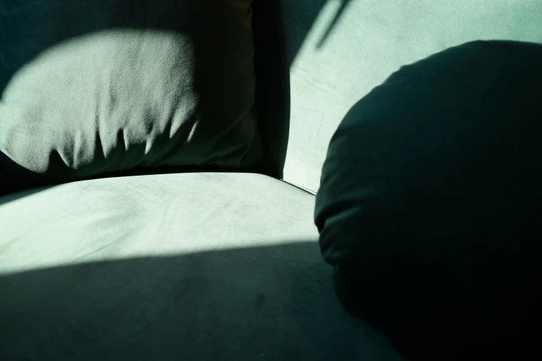 a shadow on a gray chair with a black pillow