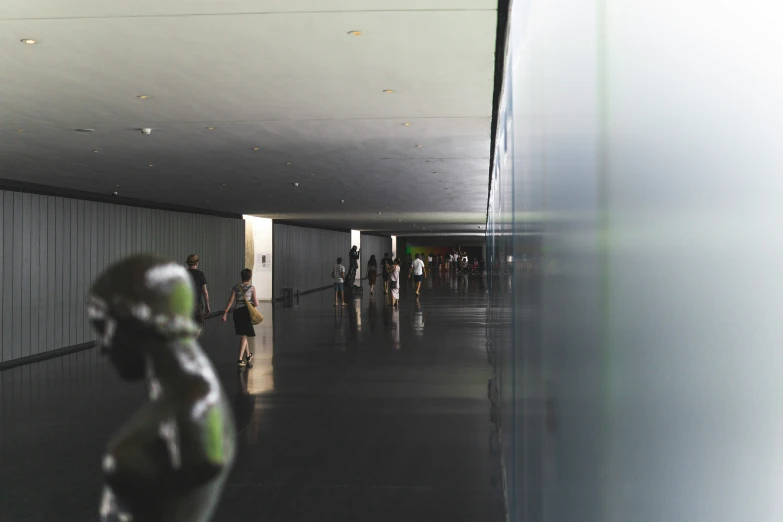 group of people walking up and down a gray hallway