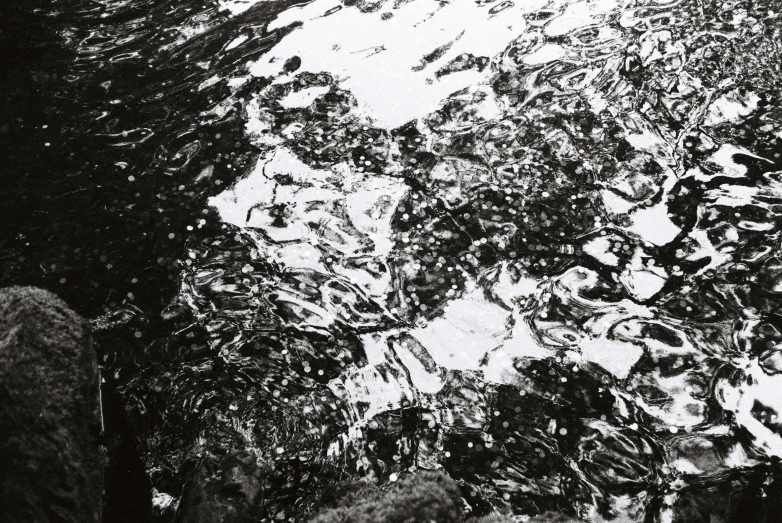 snow on a black and white picture of the surface of water