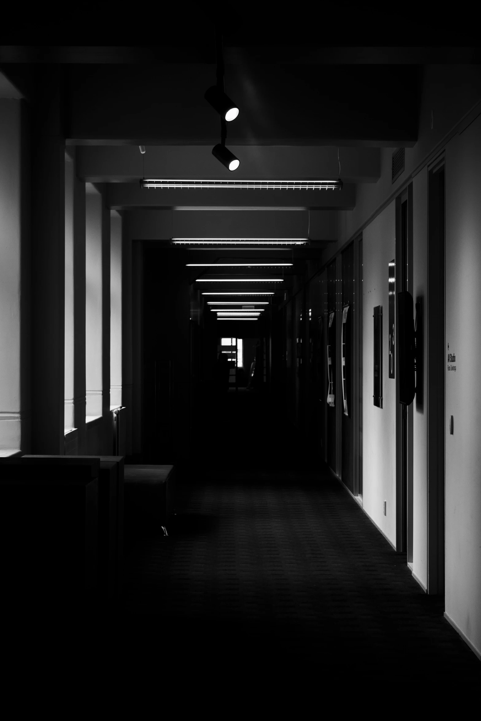 a dark hallway with bright lights and large black lighting on the ceiling