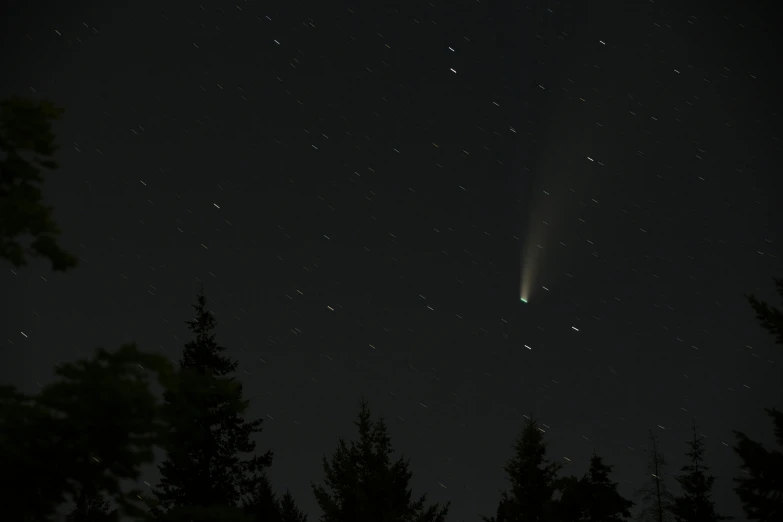 a large object flying over a forest at night