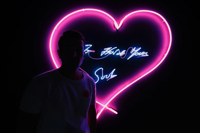 man looking at camera while standing in front of pink heart
