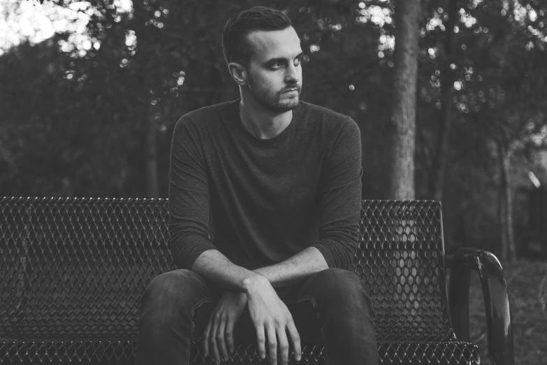 a man sitting on a park bench looking at the camera