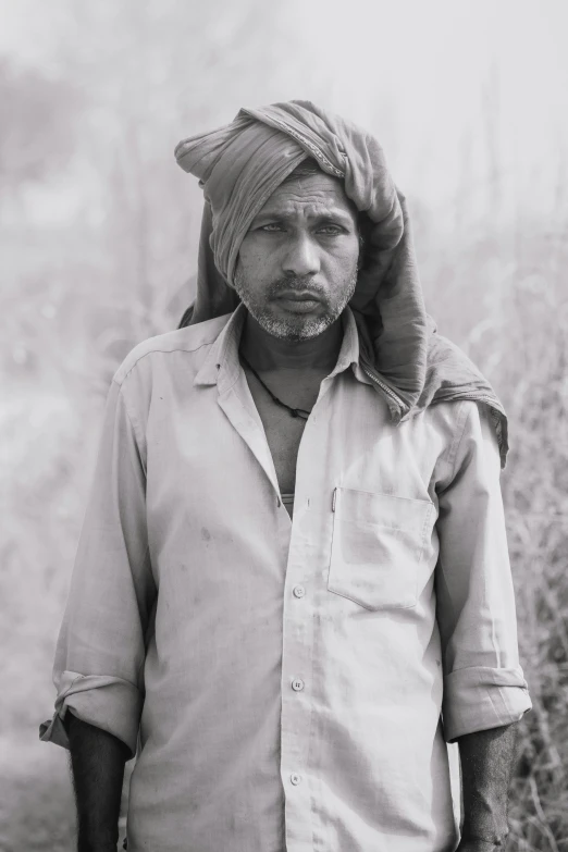 a man with a turban is standing outside in the dirt