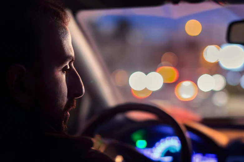 a man driving through a street at night