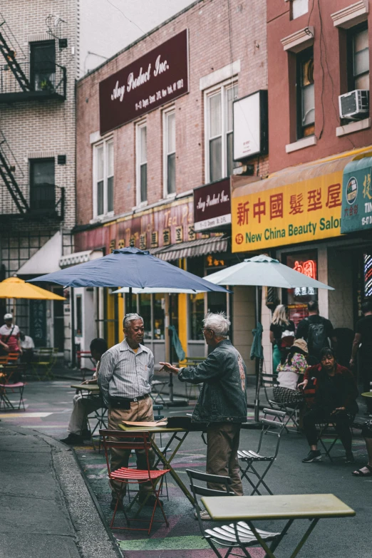 people sitting at small tables on the side of a street