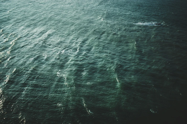 some blue ocean water a couple boats and one is alone