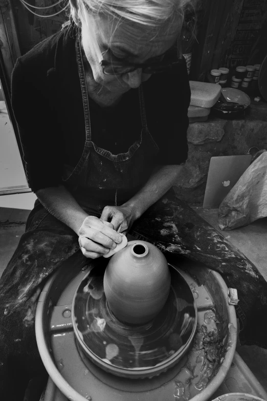 a woman in black and white is making a vase