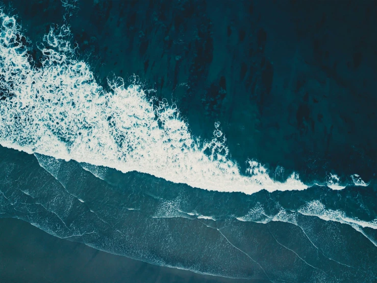 an aerial view of the ocean's blue water and foamy waves