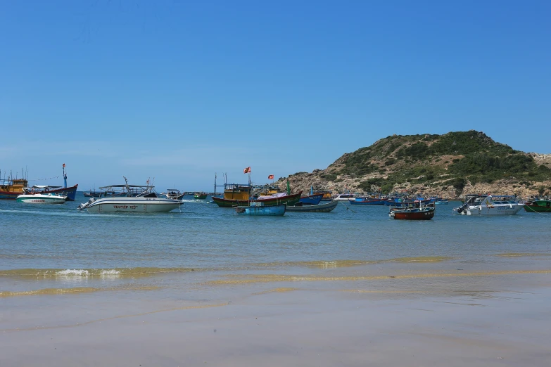 several boats are parked on the water by the beach