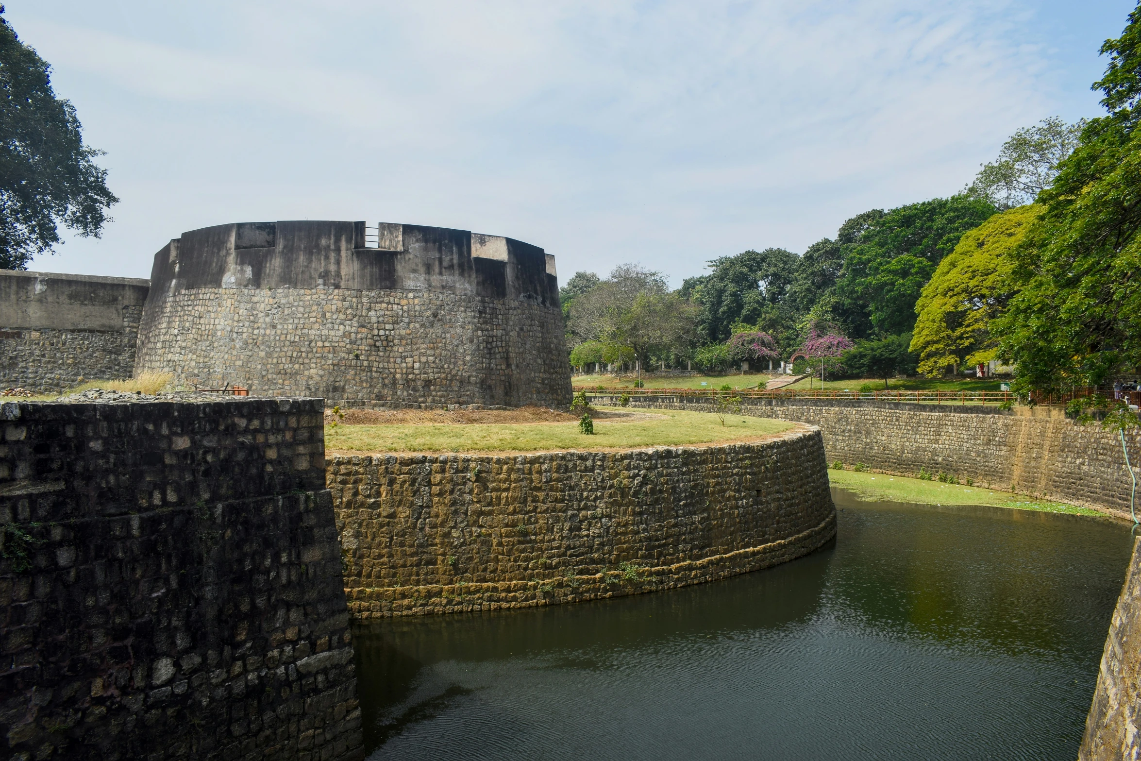 a moat leading to an old tower on a grassy hill