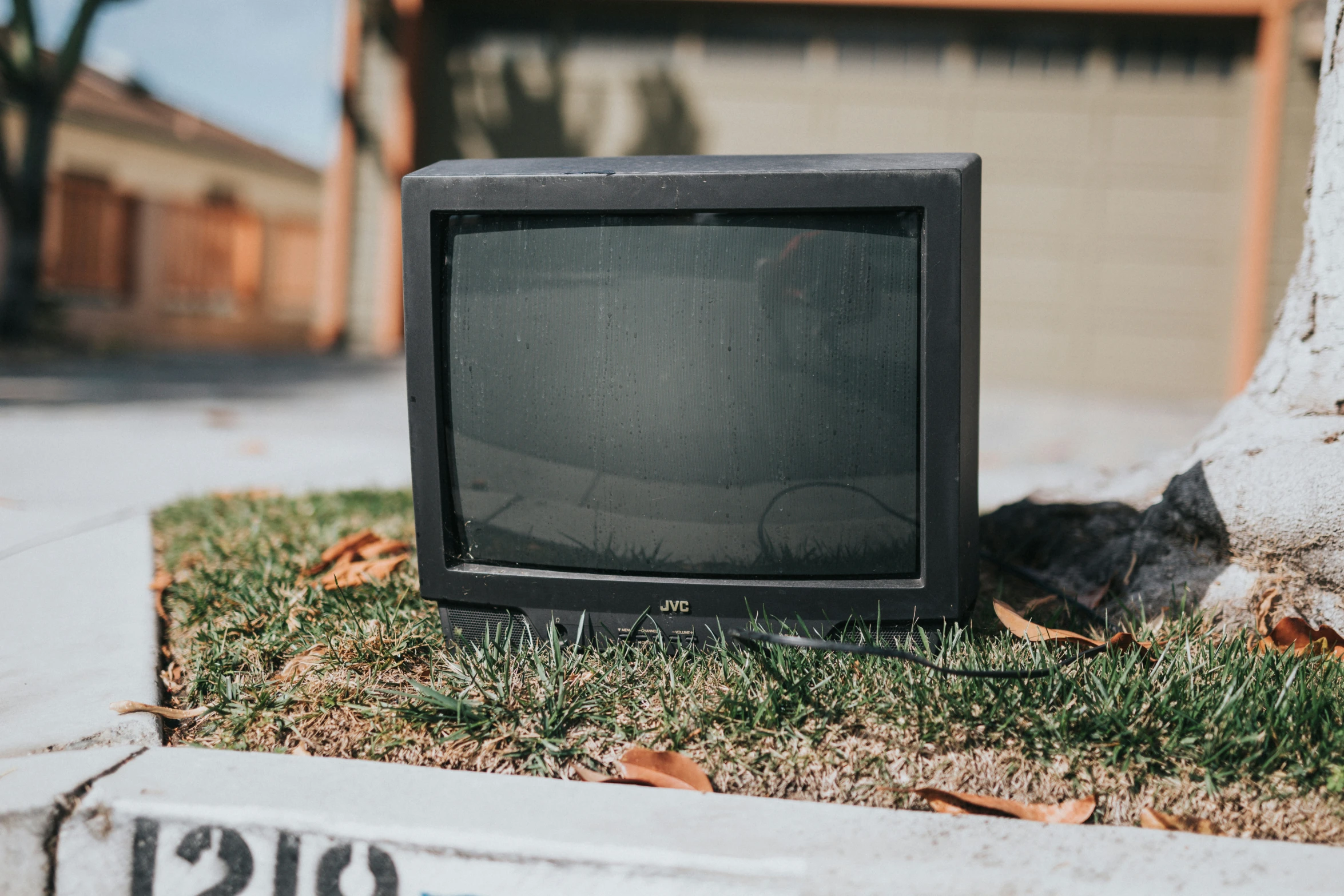 an old tv set in the grass next to a tree
