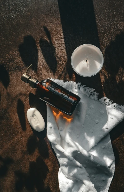 a glass bottle sits on a napkin next to an empty candle