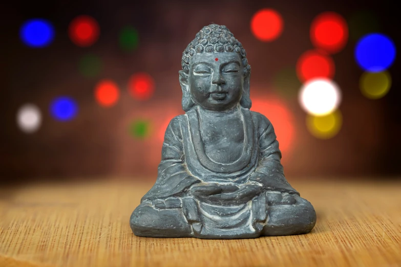 a gray buddha statue sitting on top of a wooden table