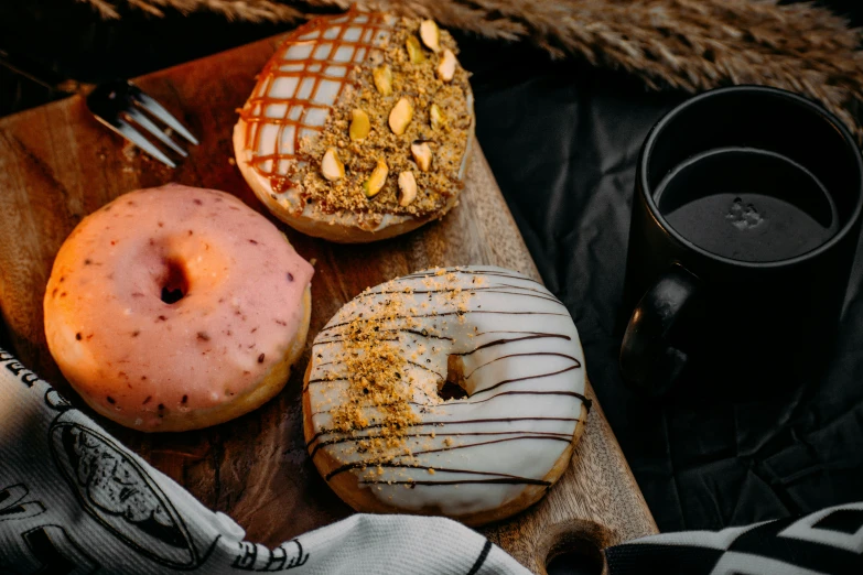 four doughnuts and two coffee cups on a wooden board