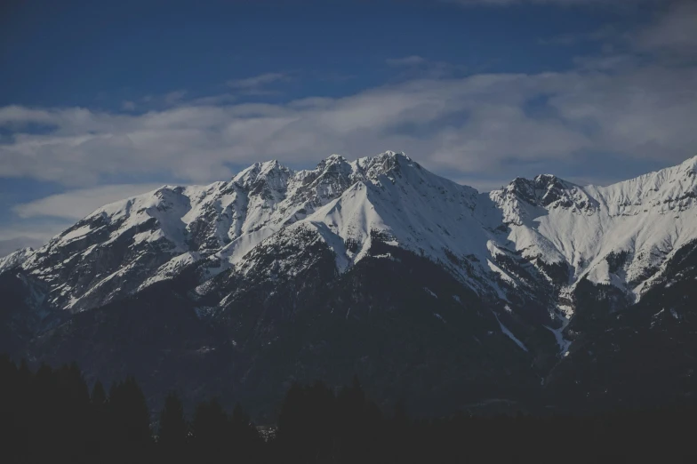 a snowy mountain with clouds in the sky