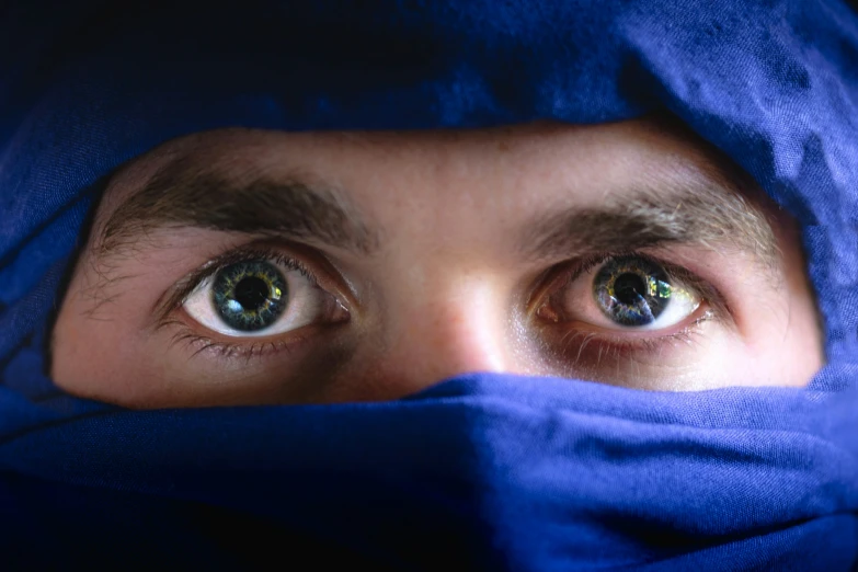 a man with green eyes is wrapped in blue cloth