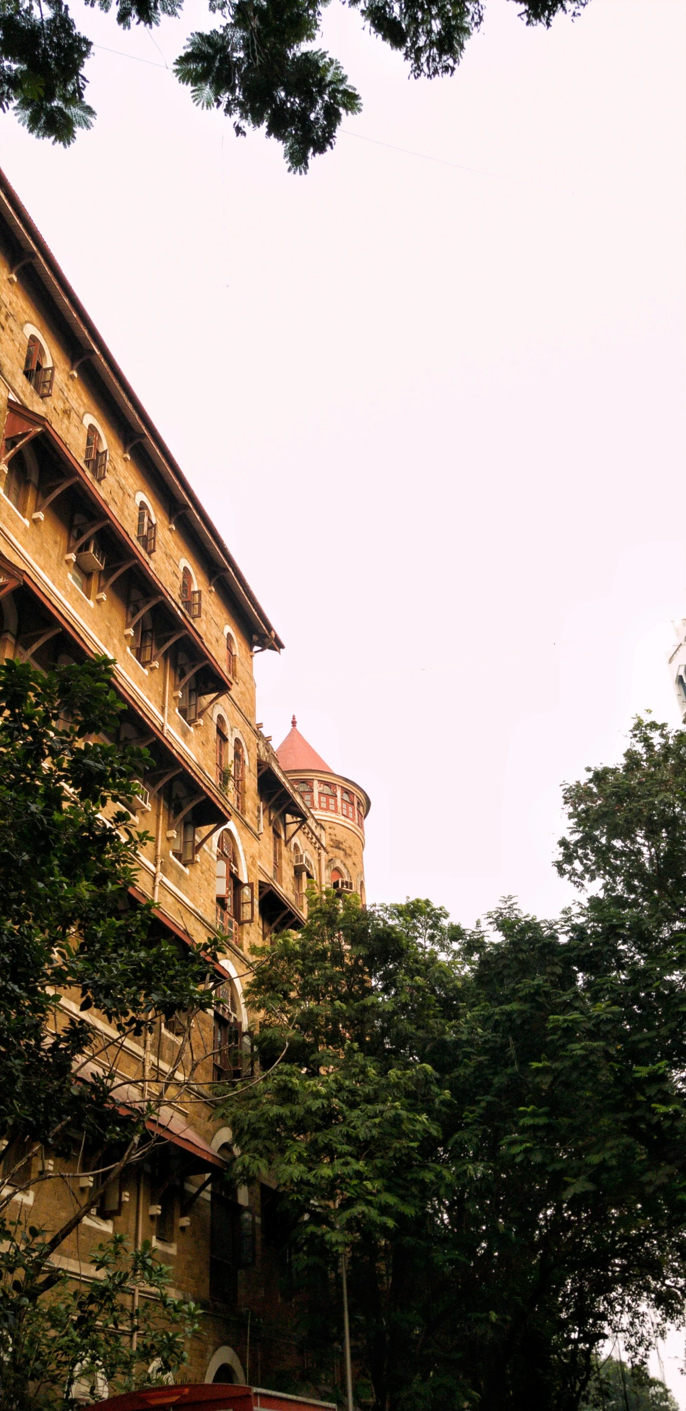 an old style building with a clock tower and a red bench