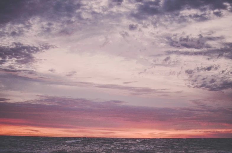 a beach at sunset with a few clouds