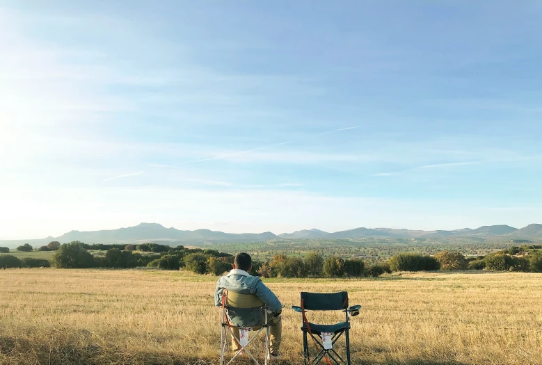 two men in a field one is riding on a cart