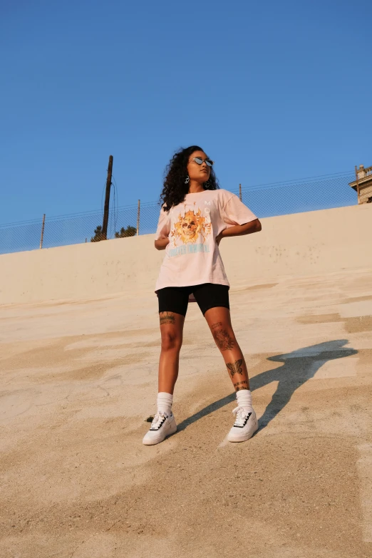 a woman with black hair in shorts, a t - shirt and sneakers on in a desert area
