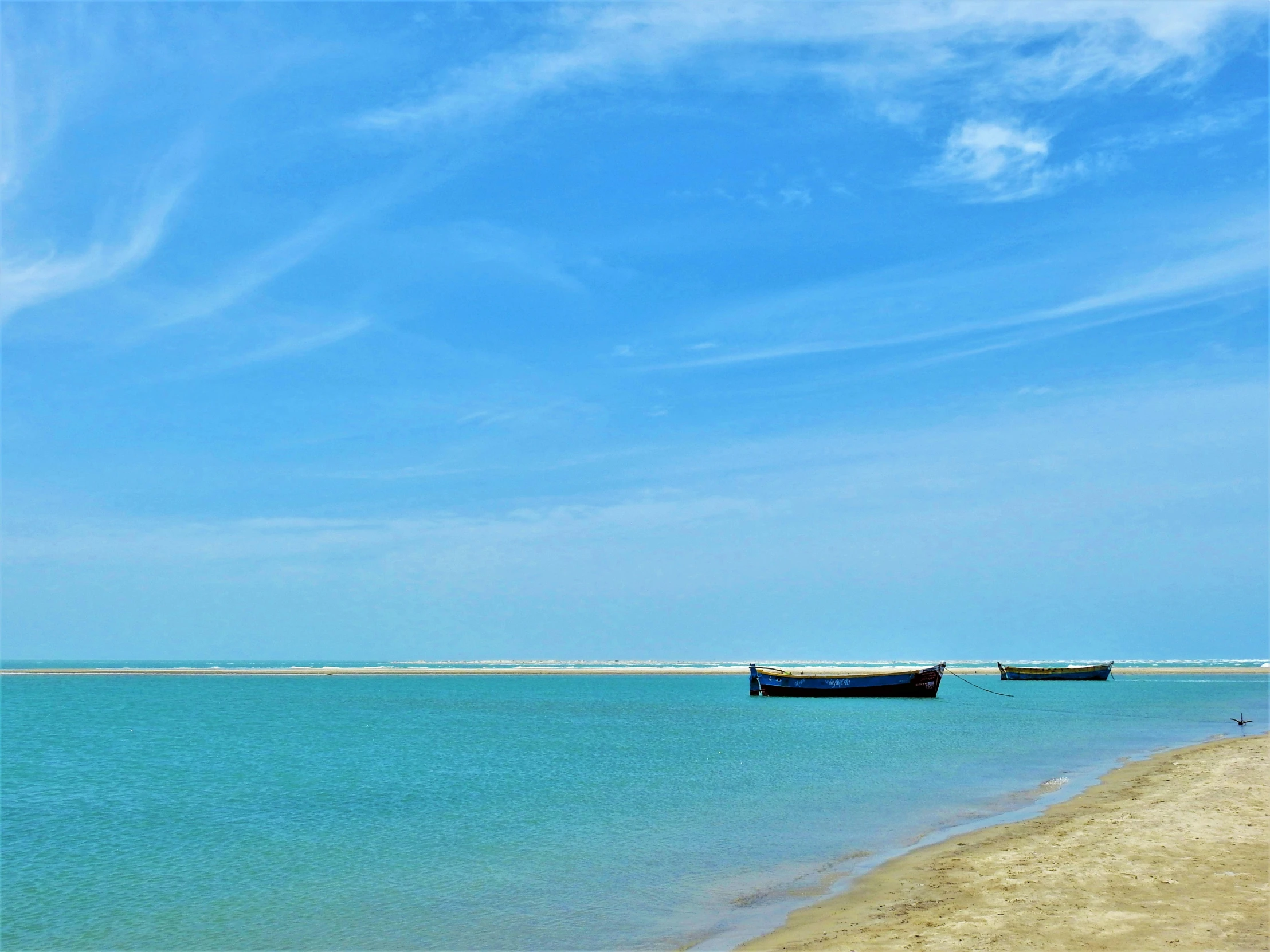 two boats anchored near the shore of a beach