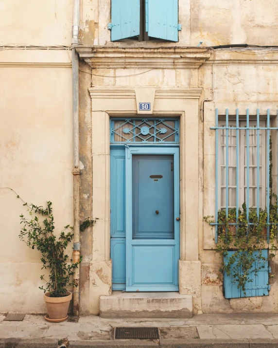 the blue door to the apartment is behind the planters