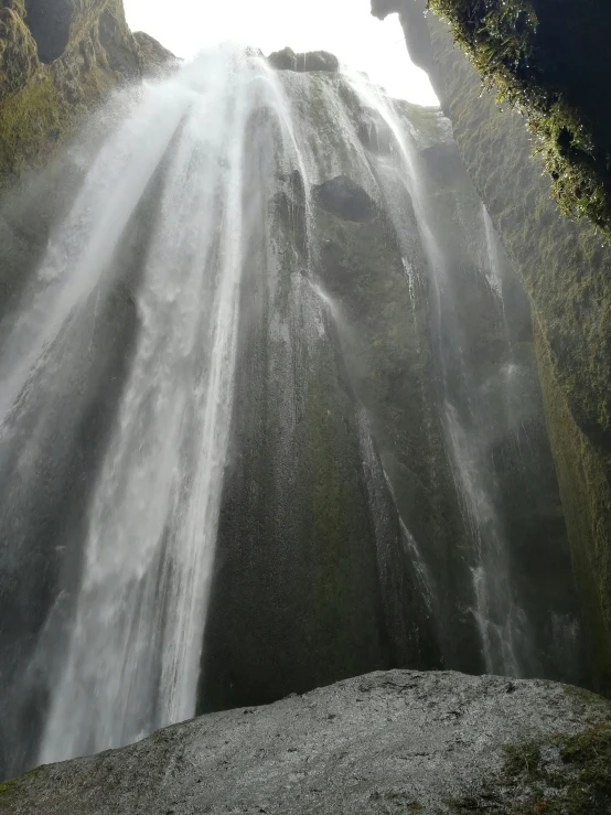 a person walks up a mountain side near the top of a waterfall