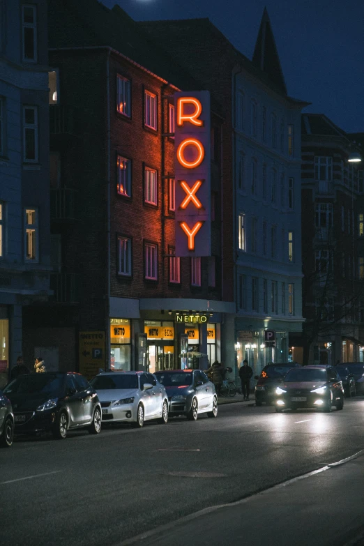 a city street at night with traffic in front of a row building