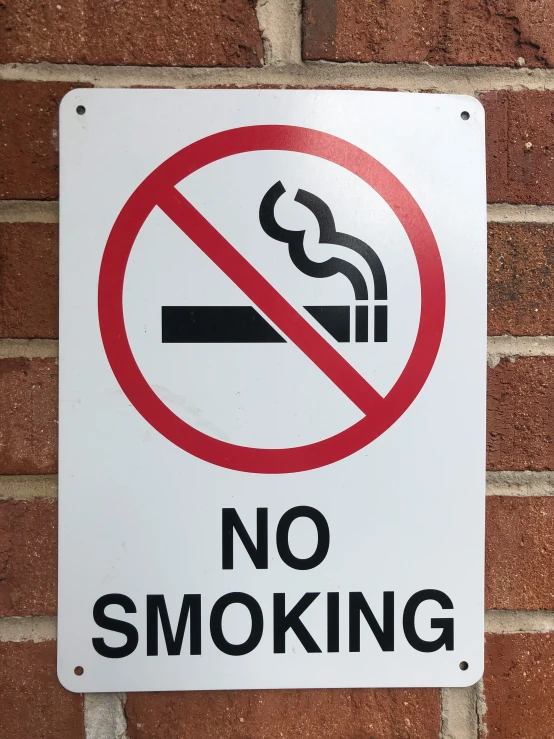 a no smoking sign posted on a brick wall