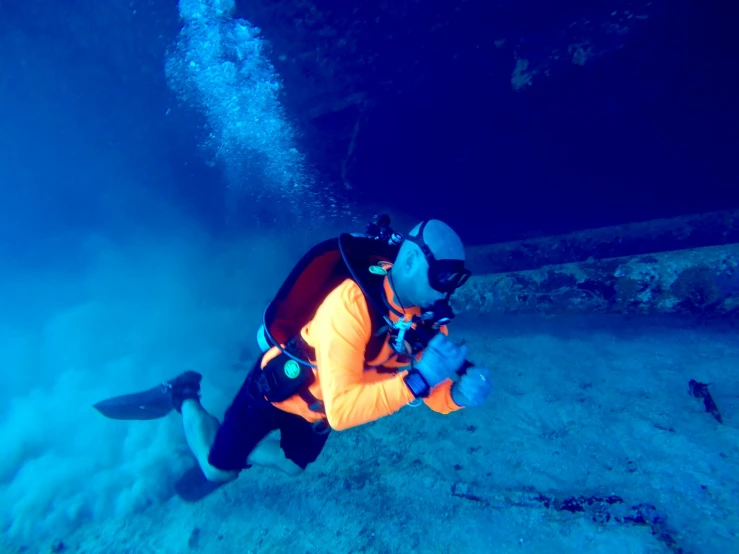 a scuba divers in blue water, looking at the bottom