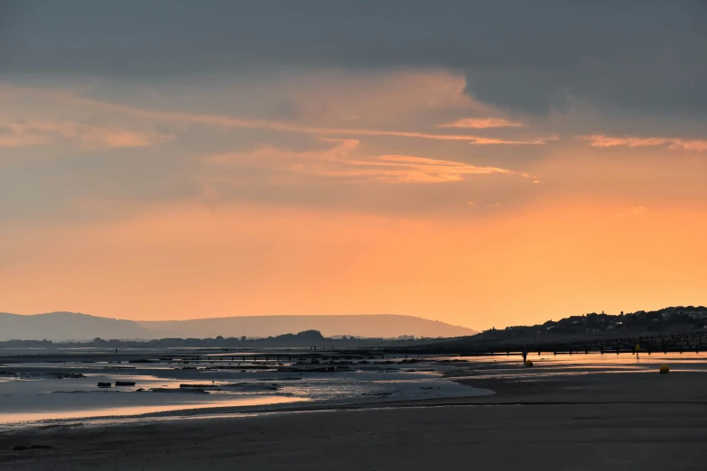 people on beach during sunset with hills in the distance