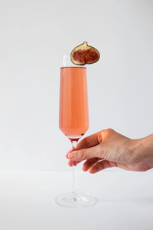 a hand is holding a wine glass with red fruit