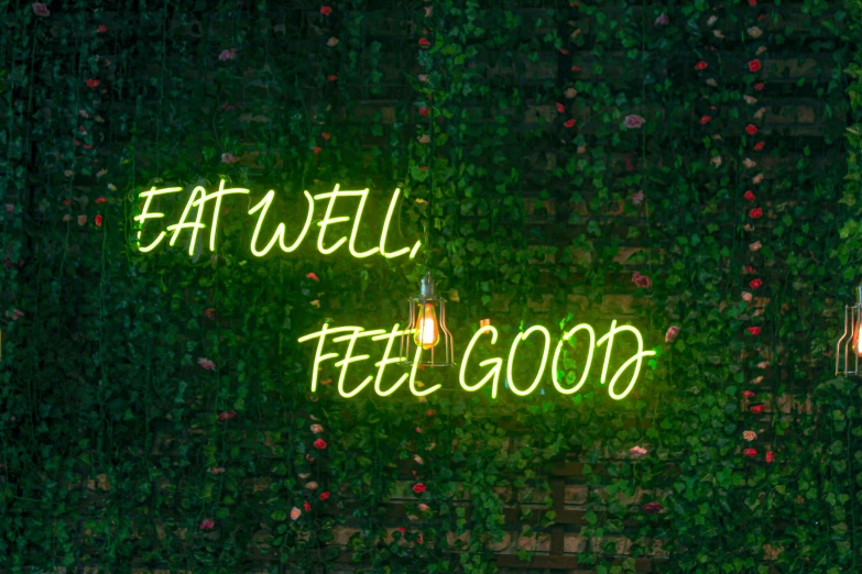 neon lights on wall with green plants and words