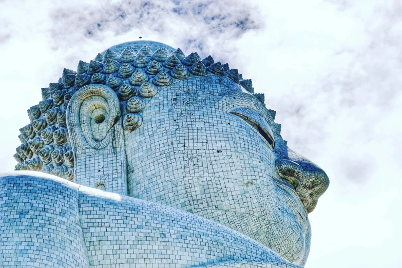 a large blue mosaic building under a cloudy sky