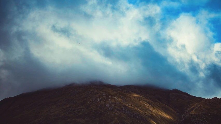 a picture of a mountain peak under clouds