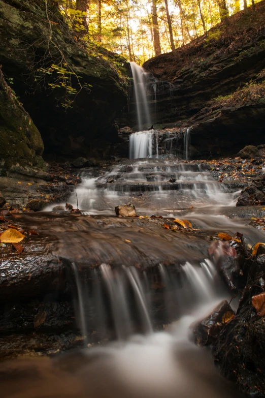 a beautiful waterfall flows down the hill in the woods