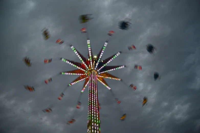 a very colorful carnival ride tower in an cloudy sky