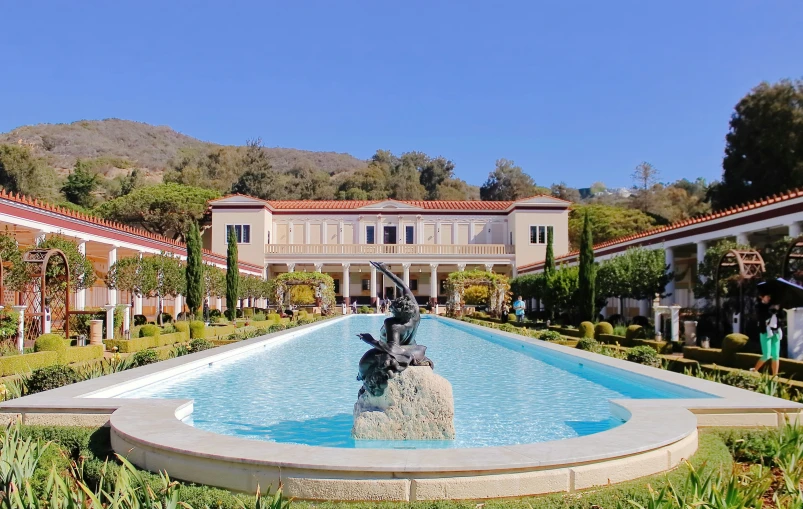 the fountain in front of the large mansion has a statue on it