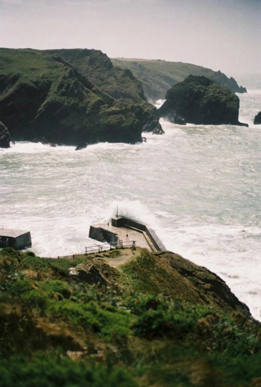 a couple of people stand on a cliff overlooking the ocean