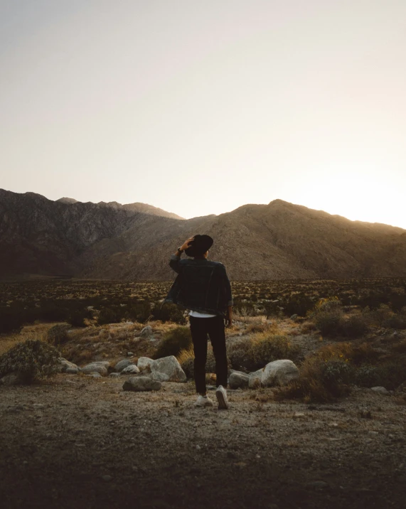 the person is on the desert land near the mountains