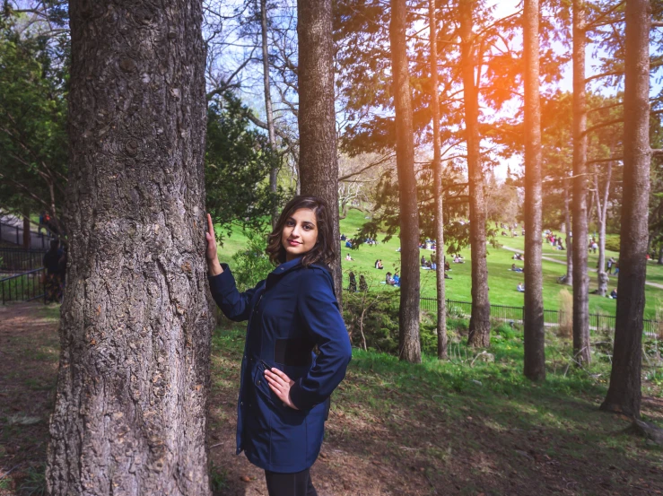 a girl standing next to a tree and smiling