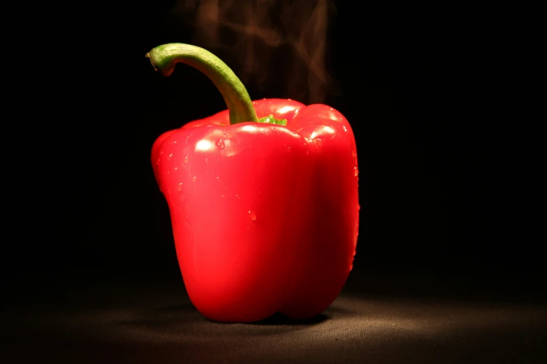 a  pepper on a black background is reflected in the lens